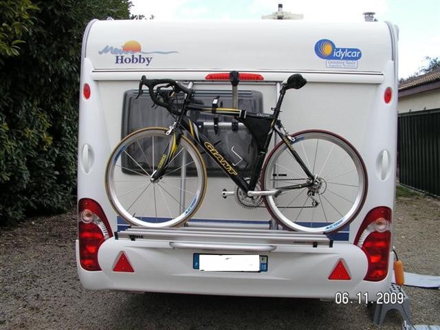 Tu vois en haut au niveau du tube supérieur du cadre on voit une petite patte brillante, c'est un bras avec un système de serrage à cliquet.<br />D'ailleurs on voit aussi le second bras pour le second vélo qui est dirigé vers le haut.